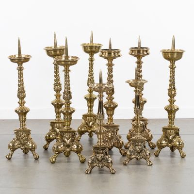 a set of six brass candlesticks on a wooden floor
