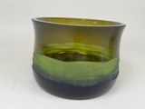 un vase vert et noir posé sur une surface blanche
