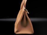 a brown handbag on a black surface with a black background
