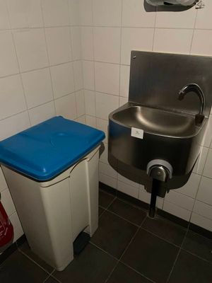 un lavabo et une poubelle dans des toilettes publiques