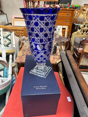 un vase bleu posé sur une boîte, elle-même posée sur une table