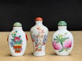 three chinese porcelain snuff bottles sitting on top of a wooden table
