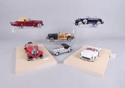four different model cars on display on a wooden stand