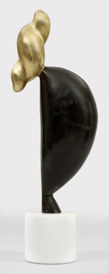 sculpture représentant un oiseau noir et doré posé sur un socle blanc