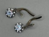 pair of diamond earrings on a hook on a gray surface