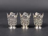 three silver vases sitting on top of a table next to each other
