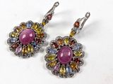 une paire de boucles d'oreilles ornées de pierres multicolores sur un fond blanc