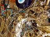 a wooden bowl filled with lots of gold and silver jewelry
