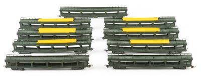 several green and yellow train cars are lined up on a white surface
