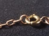 a close up of a gold chain with a ring on it