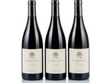 three bottles of red wine sitting next to each other on a white surface