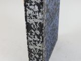 un vieux livre posé sur une table blanche, à côté d'une étiquette rose