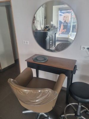 une photo d'un salon de coiffure avec un fauteuil et un miroir