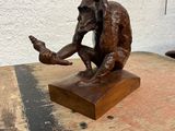 statue représentant un singe assis sur un bloc de bois, tenant une bouteille