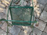 a green metal chair sitting on a brick patio