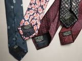 four ties with different designs are lined up on a white surface