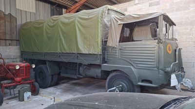 a green truck parked in a garage next to a red tractor
