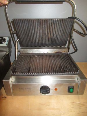 a grill that is on a table with a person holding a knife