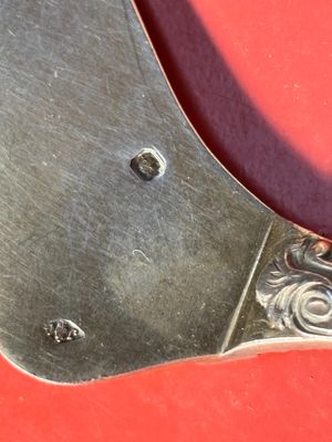 une cuillère en métal avec un manche en métal posée sur une surface rouge