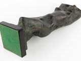 sculpture of a hand holding a green book on a white surface
