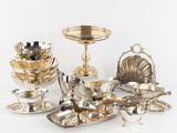 Plusieurs objets plaqués argent sont disposés sur une surface blanche