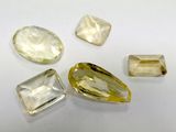 three yellow sapphires and two white sapphires on a white surface