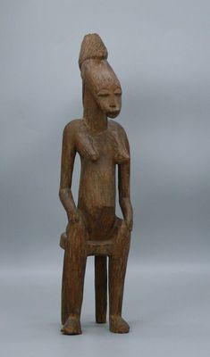 a wooden statue of a man sitting on a stool