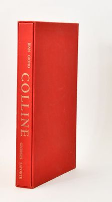 the red book is sitting on a white surface next to a white vase