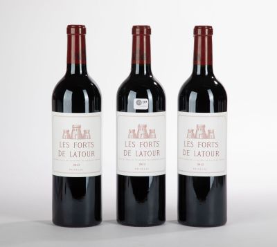 trois bouteilles de vin rouge posées l'une à côté de l'autre sur une surface blanche