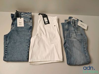 three pairs of men ' s jeans hanging on a wall