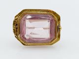 a close up of a pink stone ring on a white surface