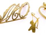 trois bijoux en or posés sur une surface blanche