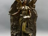 statue en bronze représentant une femme tenant un oiseau sur un rocher