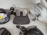 a steering wheel, pedals, and other electronics on a table