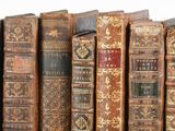 several old books are lined up on a shelf in a row