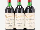 three bottles of red wine sitting next to each other on a white surface