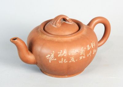 a brown teapot with writing on it sitting on a table