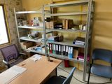 a room with a desk, chair, shelves, and a window