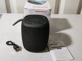 a black speaker sitting on a table next to a charger