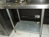a metal table with a microwave on it in a kitchen
