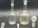three glass bottles and spoons sitting on a table