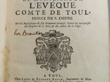 un livre ouvert sur lequel figure un blason