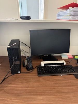 a computer desk with a monitor, keyboard, mouse and other office supplies