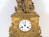 a gold clock with a statue on top of it