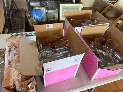 plusieurs cartons contenant des verres à vin vides posés sur une table dans un salon