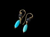 une paire de boucles d'oreilles en or et turquoise sur fond noir