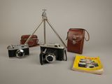 three cameras and a book on a table with a camera on a tripod