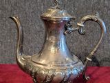 silver plated tea pot on a red cloth on a grey background
