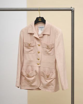 une veste rose suspendue à un cintre devant un mur beige
