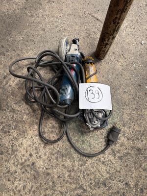 an image of a corded electric driller sitting on the ground next to a pole